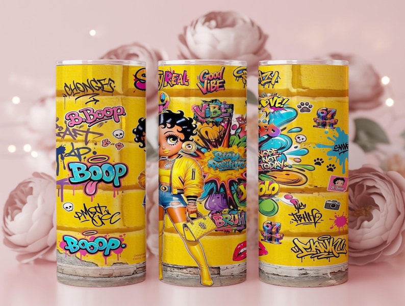 Puede incluir: Tres vasos amarillos con arte de graffiti con el personaje Betty Boop. Los vasos tienen un fondo amarillo con graffiti colorido, incluyendo la palabra "Boop" y otras frases. El dise&ntilde;o incluye im&aacute;genes de dibujos animados y colores vibrantes.