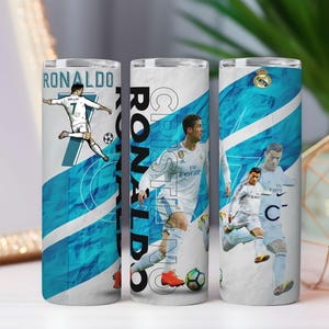 K&ouml;nnte beinhalten: Drei Edelstahlbecher mit einem wei&szlig;-blauen Design mit einem Fu&szlig;ballspieler. Auf den Bechern ist der Name "RONALDO" aufgedruckt, zusammen mit Bildern des Spielers in Aktion. Der Hintergrund hat ein blaues und wei&szlig;es Design.