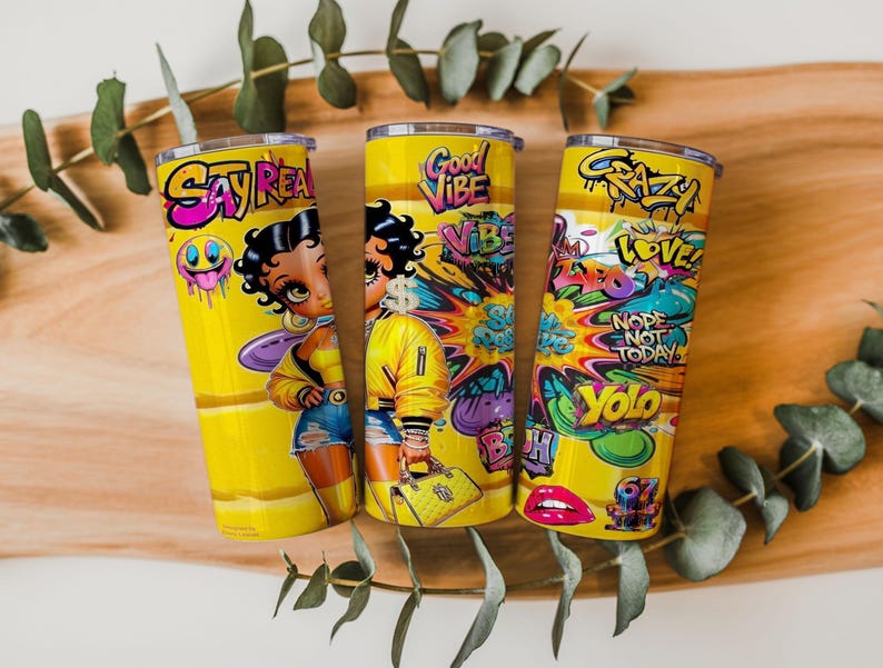Puede incluir: Tres vasos t&eacute;rmicos amarillos con gr&aacute;ficos de dibujos animados coloridos y texto. Uno presenta un personaje de dibujos animados y las palabras "Say Rea". Otro tiene "Good Vibe" y una figura de dibujos animados. El tercero tiene "Crazy", "Love", "Nope Not Today" y "Yolo".
