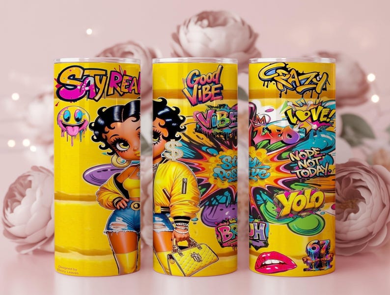 Puede incluir: Tres vasos amarillos con arte estilo grafiti. Cada vaso presenta un dise&ntilde;o diferente, incluyendo una mujer de dibujos animados, las palabras "Say Real", "Good Vibe" y "Crazy", junto con otros gr&aacute;ficos coloridos. Los vasos son cil&iacute;ndricos.