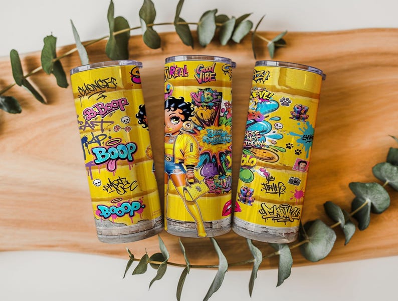 Puede incluir: Tres vasos aislados amarillos con arte de graffiti y un personaje de dibujos animados. Los vasos presentan las palabras "Boop" y "Good Vibe" en un estilo graffiti. El personaje de dibujos animados lleva una chaqueta amarilla y sostiene una bolsa morada.