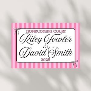Könnte beinhalten: Ein rosa-weiß gestreiftes Schild mit den Worten "Homecoming Court" oben. Die Namen "Riley Fowler & David Smith" sind in eleganter Schrift geschrieben, darunter "2025". Das Schild ist mit kleinen Schleifen verziert.