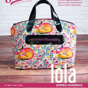 Könnte beinhalten: Gewölbte Handtasche mit buntem Blumen- und Fuchsdruck. Die Tasche hat eine schwarze Reißverschlusstasche und Griffe. Die Tasche ist 33 cm breit, 20 cm hoch und 15 cm tief.