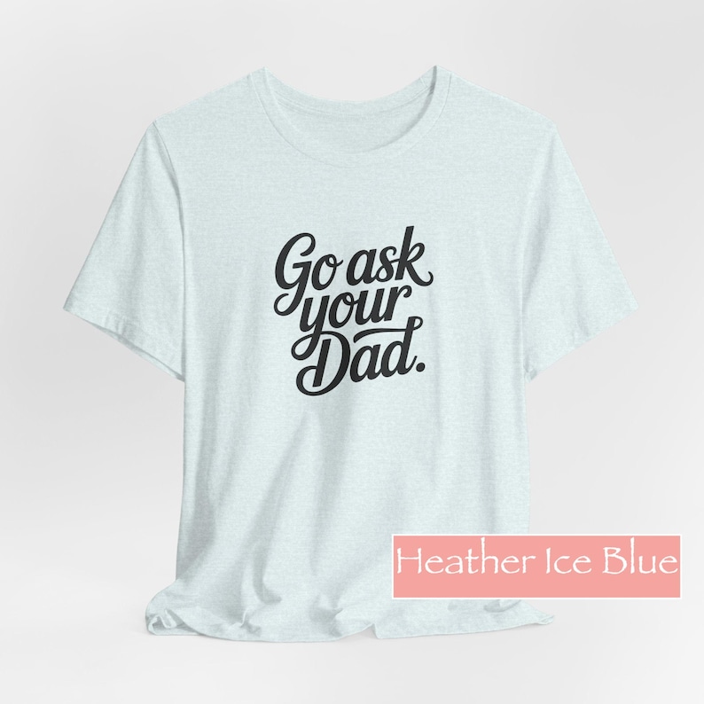 May include: A light blue t-shirt with the words "Go ask your Dad" in black script. The shirt is a heather ice blue colour and has a crew neck. The text is centered on the front of the shirt.