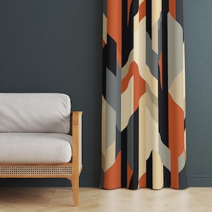 Könnte beinhalten: Gemusterter Vorhang mit geometrischem Design in Orange-, Schwarz-, Grau- und Beigetönen. Der Vorhang hängt vor einer dunkelblauen Wand. Links vom Vorhang befindet sich ein hellgraues Sofa mit Holzarmen.