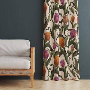 Puede incluir: Cortina color crema con un estampado floral repetido que presenta flores en forma de alcachofa en tonos naranja, morado y marrón, sobre tallos y hojas verdes. La cortina cuelga frente a una pared azul oscuro.