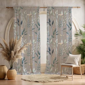 Könnte beinhalten: Zwei transparente Vorhänge mit einem botanischen Druck aus grünen und blauen Blättern und Blumen auf taupefarbenem Hintergrund. Die Vorhänge hängen an einer Holzstange. Ein Stuhl, ein Teppich und dekorative Vasen befinden sich vor den Vorhängen.