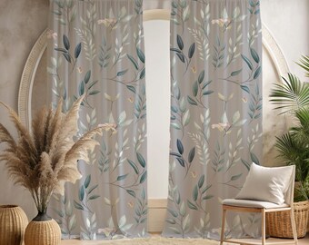 May include: Two sheer window curtains with a botanical print of green and blue leaves and flowers on a taupe background. The curtains are hanging on a wooden rod. A chair, rug, and decorative vases are in front of the curtains.