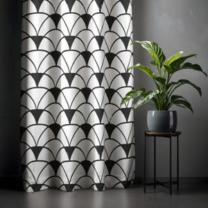 May include: A white curtain with a black fan-shaped pattern. A potted plant with green leaves sits on a small, dark brown table with black legs. The curtain is in front of a grey wall.