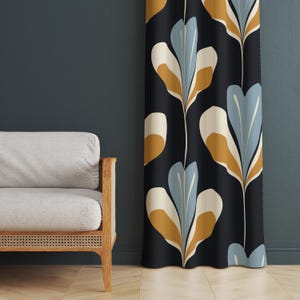 Könnte beinhalten: Ein dunkler Vorhang mit einem sich wiederholenden Blumenmuster in Blau-, Creme- und Goldtönen. Der Vorhang hängt vor einer dunkelblauen Wand. Links befindet sich ein hellgraues Sofa mit Holzarmlehnen.