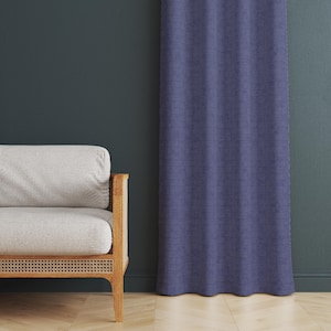 May include: A blue curtain with a textured, brick-like pattern hangs next to a light-colored sofa with wooden arms. The sofa has a woven cane base. The wall behind the sofa is a dark teal color.