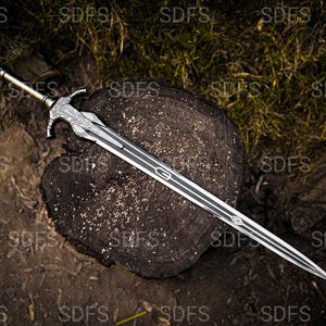 May include: A detailed sword with a silver blade and a decorative hilt, resting on a weathered wooden surface. The blade features a central groove and intricate designs. The hilt has a detailed pattern and a gold-colored pommel. The sword is a fantasy weapon.