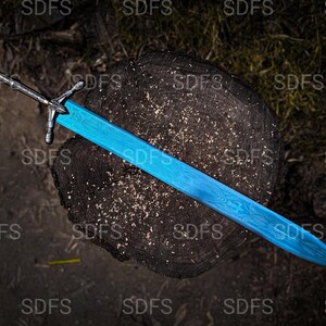 May include: A detailed overhead shot of a sword with a bright blue blade and a silver handle. The blade has a patterned design. The sword rests on a dark, textured wooden surface.