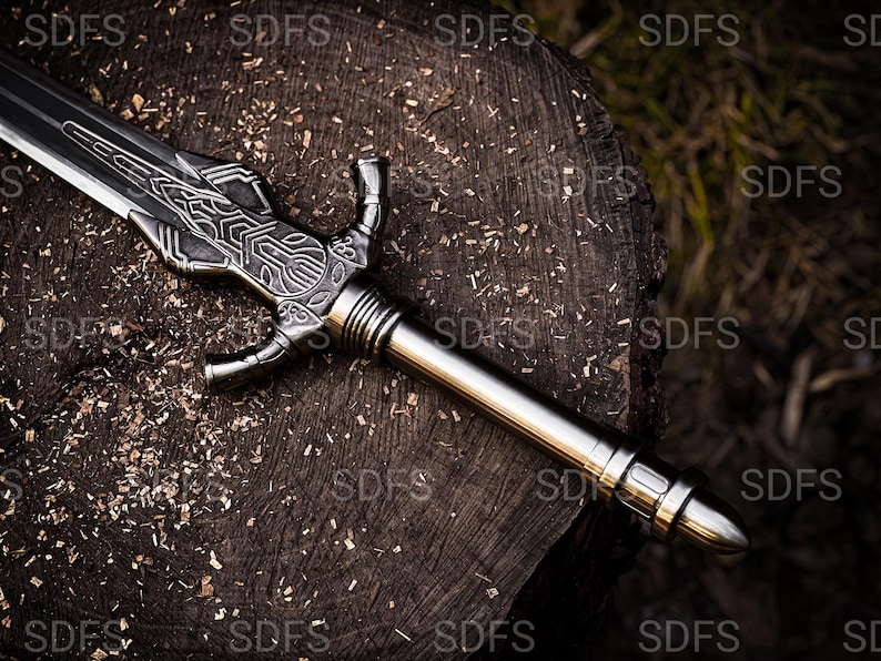 May include: A detailed, silver-colored sword with an ornate handle and blade design. The sword is resting on a weathered, dark brown wooden surface, with wood shavings scattered around it. The sword's blade is approximately 24 inches long.
