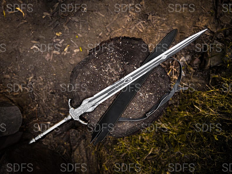 May include: A silver and black sword with a decorative handle and a long, pointed blade rests on a tree stump. A black sheath with a shoulder strap lies beside the sword. The background is a mix of wood and foliage.