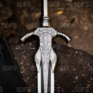 May include: A detailed close-up of a silver sword with an ornate hilt and a black leather sheath. The sword's blade is silver with a black center. The hilt features intricate designs. The sword rests on a wooden surface, suggesting a historical or fantasy theme.