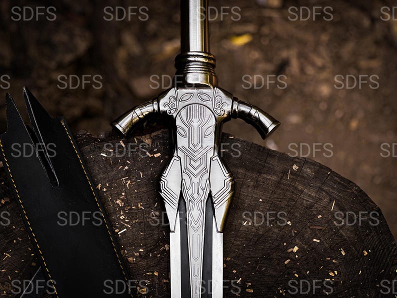 May include: A detailed close-up of a silver sword with an ornate hilt and a black leather sheath. The sword's blade is silver with a black center. The hilt features intricate designs. The sword rests on a wooden surface, suggesting a historical or fantasy theme.