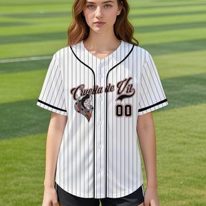 May include: White baseball jersey with black pinstripes, black trim, and the text "Cruella de Vil" in a stylized font. The jersey features a graphic of Cruella de Vil and the number "00".
