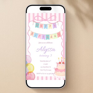 May include: A smartphone displays a birthday invitation with a pink and pastel color scheme. The invitation features a banner that reads "Happy Birthday" and includes the name "Alyssa" and the number "3". A cake and balloons are also depicted.