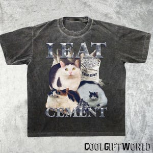 Pode incluir: Camiseta cinza escuro com um gr&aacute;fico com quatro gatos e as palavras "I EAT CEMENT" em uma fonte met&aacute;lica. Um gato est&aacute; ao lado de um saco de cimento. A camiseta tem um visual vintage e desgastado, com o texto "COOLGIFTWORLD" na parte inferior.