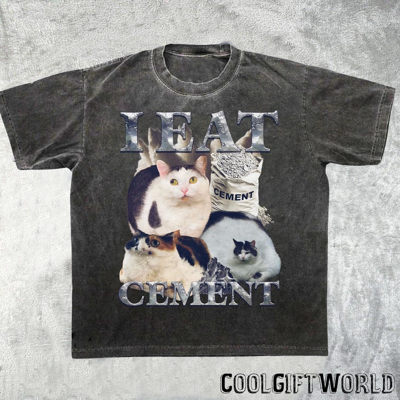 Pode incluir: Camiseta cinza escuro com um gr&aacute;fico com quatro gatos e as palavras "I EAT CEMENT" em uma fonte met&aacute;lica. Um gato est&aacute; ao lado de um saco de cimento. A camiseta tem um visual vintage e desgastado, com o texto "COOLGIFTWORLD" na parte inferior.