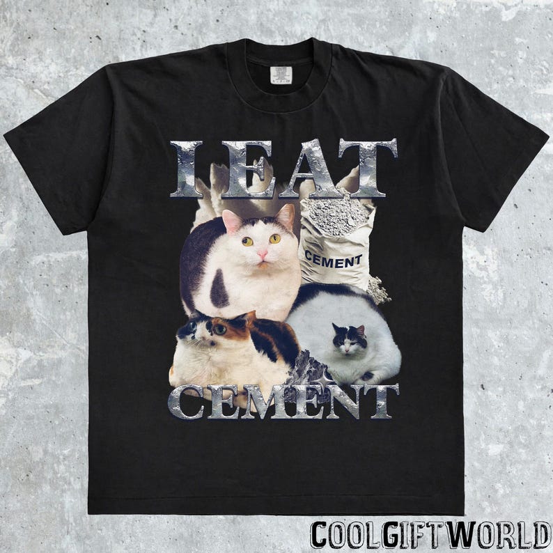 Pode incluir: Camiseta preta com um design gr&aacute;fico com quatro gatos e as palavras "I EAT CEMENT" em fonte prateada texturizada. Uma saca de cimento tamb&eacute;m est&aacute; no design. A camiseta tem gola redonda e mangas curtas.