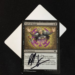 May include: A Magic: The Gathering card called "Seal of Doom". It is a purple and gold enchantment card with a woman in armor on the front. The card text reads "Sacrifice Seal of Doom: Destroy target nonland creature. It can't be regenerated."