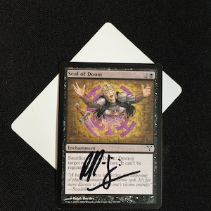 Può includere: Una carta nera e viola di Magic: The Gathering con il titolo "Sigillo della Perdizione". La carta è un incantesimo con un costo di 2 mana incolore. Il testo della carta recita: "Sacrificare Sigillo della Perdizione: Distruggi la creatura bersaglio. Non può essere rigenerata."