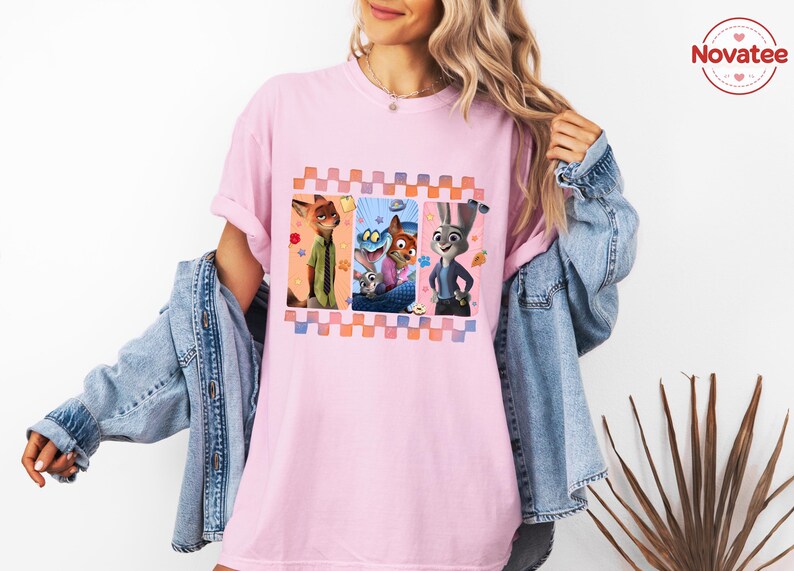 Może przedstawiać: Jasnor&oacute;żowa koszulka z kolorową grafiką postaci z animowanego filmu Zwierzogr&oacute;d. Grafika jest obramowana wzorem w kratę. Koszulka ma swobodny, obszerny kr&oacute;j.