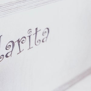 May include: A white wooden box with the word "Clarita" written in cursive on the top.