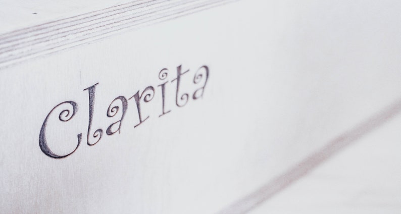May include: A white wooden box with the word "Clarita" written in cursive on the top.