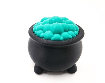 May include: A black cauldron with three small feet, filled with bright teal bubbles. The cauldron has a rounded shape with a wide rim. The bubbles are clustered together, filling the top of the cauldron. The background is plain white.