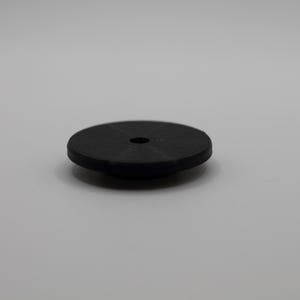 May include: A small, circular black disc with a smooth, flat top surface and a centered circular hole. The object features a slightly beveled edge and a stepped base design, presenting a solid, uniform matte black finish throughout its structure.
