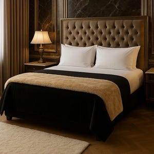 Könnte beinhalten: Ein Bett mit einem hohen, gesteppten braunen Kopfteil, zwei weißen Kissen, einer einfarbigen schwarzen Tagesdecke und einer strukturierten beigen Kunstfelldecke, die über das Fußende des Bettes drapiert ist. Das Bett steht neben einer Lampe.