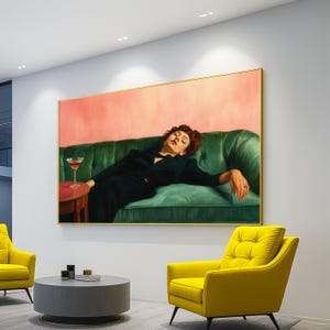 Pode incluir: Uma pintura emoldurada retrata uma pessoa reclinada em um sofá de veludo verde, com um coquetel em uma pequena mesa vermelha. O fundo é rosa suave, e a pintura está situada em um interior moderno com poltronas amarelas e uma mesa de centro cinza.