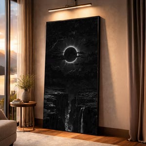 Può includere: Una grande stampa su tela in bianco e nero incorniciata raffigurante un'eclissi solare sopra un paesaggio di canyon. L'opera presenta un anello luminoso attorno a una sfera scura, con una cascata che scende lungo le pareti del canyon. Il tema generale è una scena naturale drammatica.