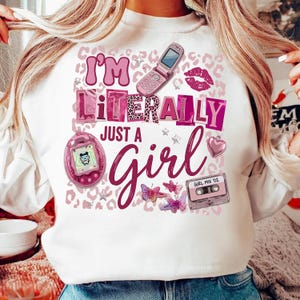 以下が含まれることがあります： 「I'm Literally Just a Girl」と書かれたピンク色のグラフィックが特徴の白いスウェットシャツ。デザインには、フリップフォン、たまごっち、カセットテープ、蝶、ハートが含まれています。