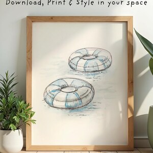 May include: Watercolor print of two blue and white striped inner tubes floating on water. The artwork is framed in a light wood frame. The text "Download, Print & Style in your space" is at the top.