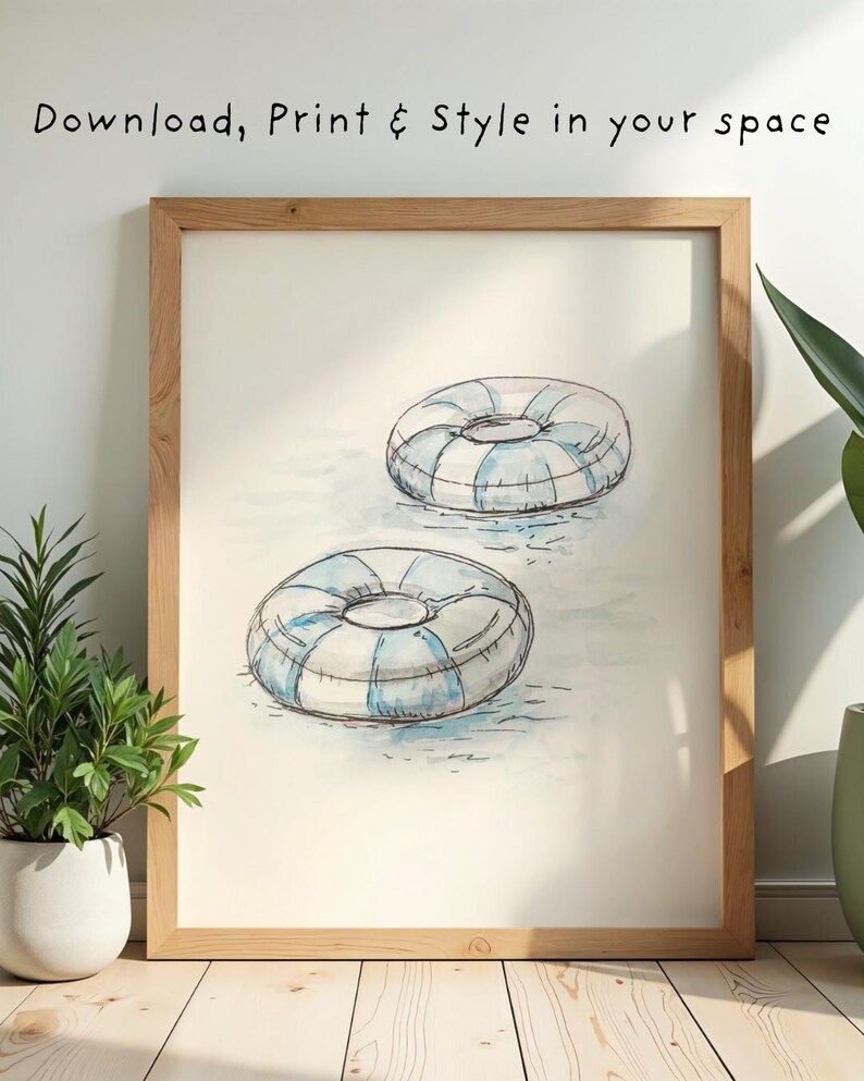 May include: Watercolor print of two blue and white striped inner tubes floating on water. The artwork is framed in a light wood frame. The text "Download, Print & Style in your space" is at the top.