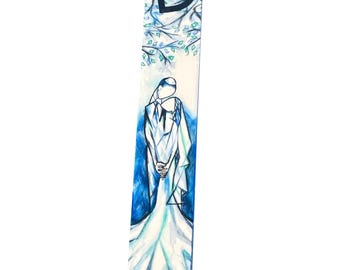 Può includere: Un astuccio per mezuzah con un design ad acquerello. La parte superiore presenta una lettera ebraica nera e un motivo a ramo d'albero con foglie verdi. Il corpo dell'astuccio raffigura una coppia in abito da sposa e abito. Lo sfondo è blu e bianco.