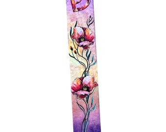 Può includere: Un astuccio per mezuzah rettangolare dipinto a mano con un design ad acquerello. L'astuccio presenta un gradiente di viola, rosa e beige, con due papaveri rossi e steli verdi. La lettera ebraica 'Shin' è in alto.