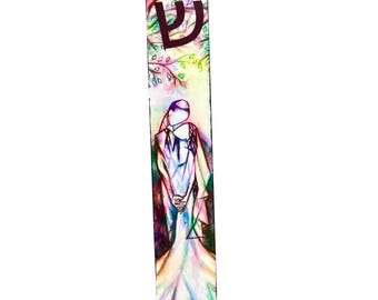 Può includere: Un colorato astuccio per mezuzah con un'illustrazione ad acquerello. La parte superiore presenta una lettera ebraica e un disegno ad albero. La parte inferiore raffigura una figura in un lungo vestito. L'opera è nei toni del verde, rosa, viola e giallo.