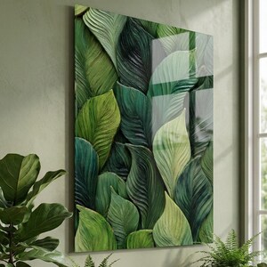 May include: A rectangular wall art piece featuring a high-gloss finish and a detailed, layered illustration of overlapping tropical leaves in various shades of deep forest green, emerald, and light lime green with visible textured veins.