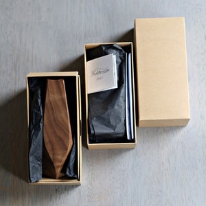 May include: Two brown cardboard boxes with black tissue paper inside. One box contains a wooden tie, and the other box contains a card with the text "Woodstorming 2014".