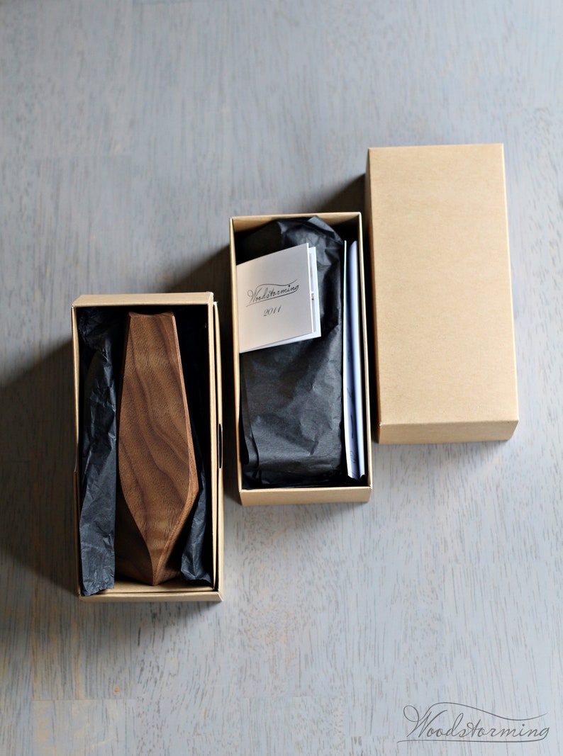 May include: Two brown cardboard boxes with black tissue paper inside. One box contains a wooden tie, and the other box contains a card with the text "Woodstorming 2014".