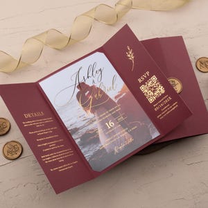 Op de afbeelding: Bordeaux trouwuitnodigingssuite met gouden foliedetails. De uitnodiging toont een foto van een stel en de namen "Ashley & Ariel" met de datum "16". Inclusief RSVP-informatie en zegelwas.