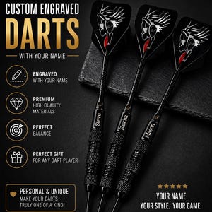 Op de afbeelding: Drie zwarte metalen darts met getextureerde barrels, elk gegraveerd met de namen Steve, Sascha en Mason. De flights bevatten een witte afbeelding van een schedel met een koptelefoon. De tekst op de afbeelding luidt CUSTOM ENGRAVED DARTS.