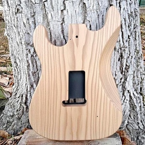 Puede incluir: Una taza de cer&aacute;mica blanca con un asa negra y el texto "But First, Coffee" en un estilo manuscrito. La taza est&aacute; sobre una superficie blanca. La taza mide aproximadamente 10 cm de alto.