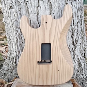 May include: A white ceramic mug with a black handle and the text "But First, Coffee" in a black, handwritten-style font. The mug is on a white surface.