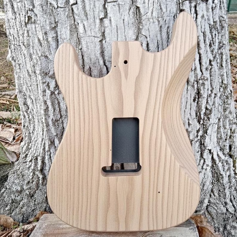 May include: A white ceramic mug with a black handle and the text "But First, Coffee" in a black, handwritten-style font. The mug is on a white surface.